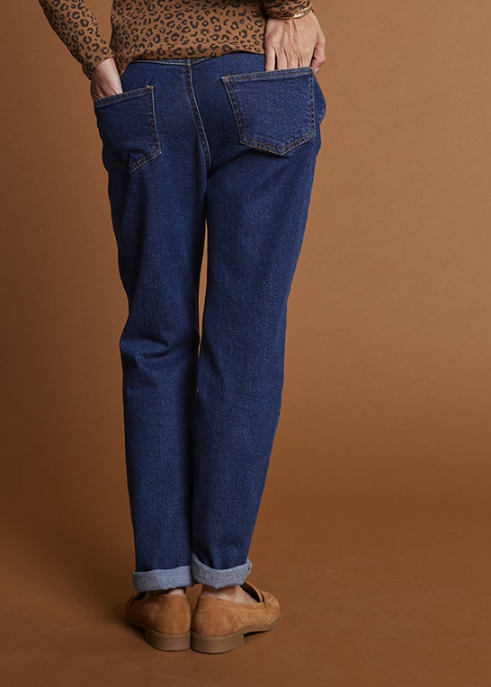 Person wearing blue jeans and brown shoes against a brown background
