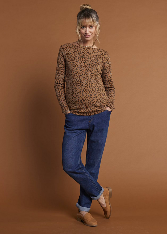 Woman wearing a brown leopard print sweater and blue jeans against a brown background