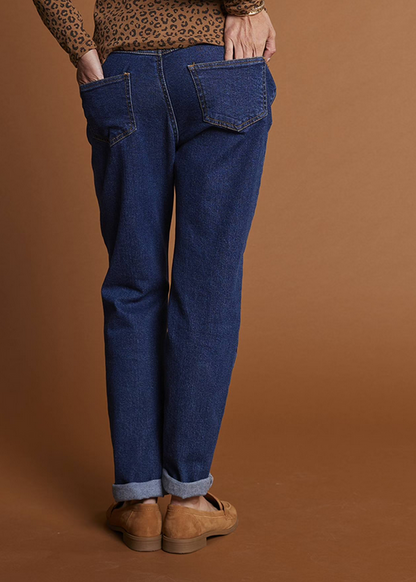 Person wearing blue jeans and brown shoes against a brown background
