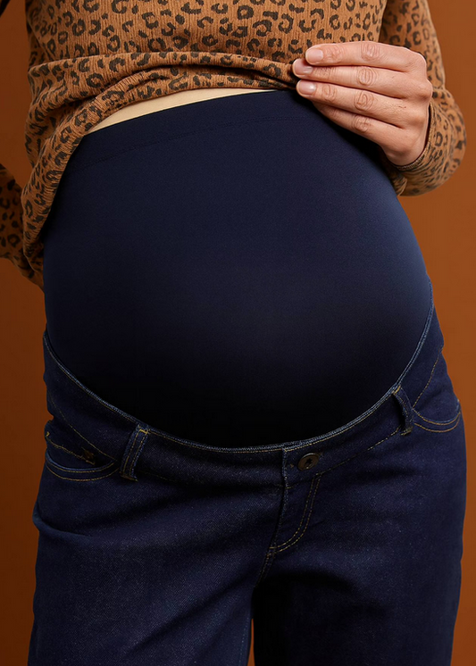 Person wearing a leopard print top and dark blue jeans against an orange background