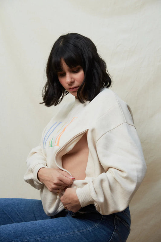 Person wearing a white jacket with a cut-out design, sitting against a plain background